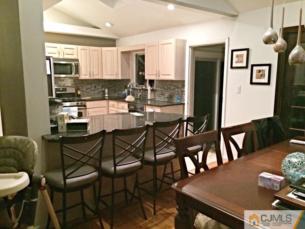 6 Colburn Road East Brunswick, NJ 08816 - Photo 7 of 24 a kitchen with stainless steel appliances granite countertop a dining table chairs and a refrigerator