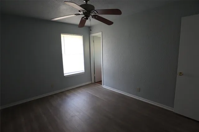 an empty room with a window and a fan