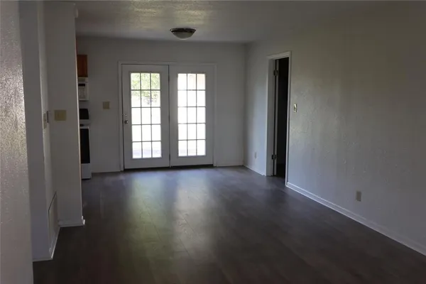 an empty room with wooden floor and windows with curtains