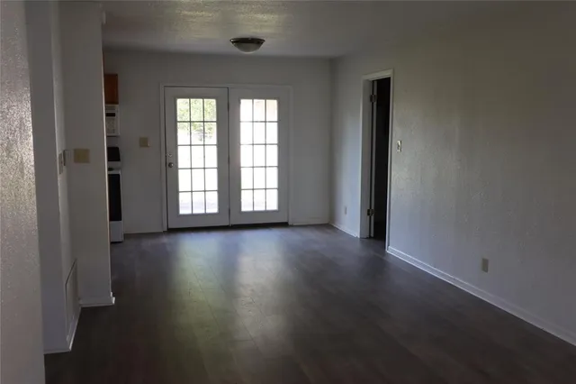 an empty room with wooden floor and windows with curtains