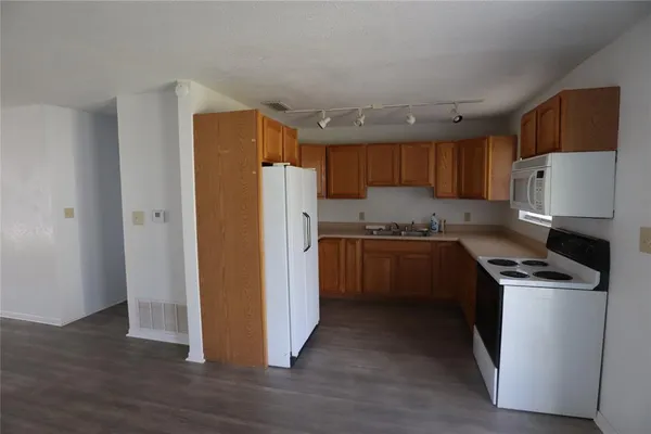 a kitchen with a refrigerator a stove top oven and wooden floor