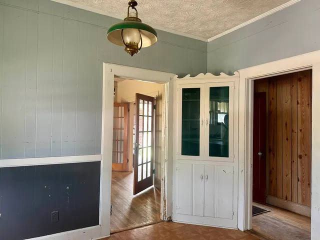 a view of a hallway with wooden floor and chandelier