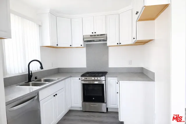 a kitchen with stainless steel appliances granite countertop a stove a sink and a refrigerator