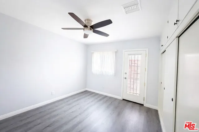 an empty room with wooden floor fan and windows