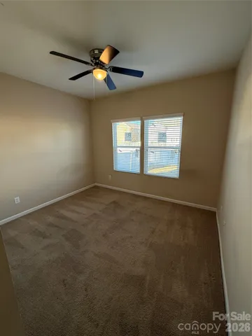 a view of an empty room with window and chandelier fan