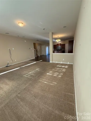 a view of an empty room with window and a kitchen