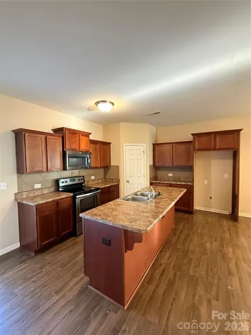 a large kitchen with a large counter top stainless steel appliances and cabinets
