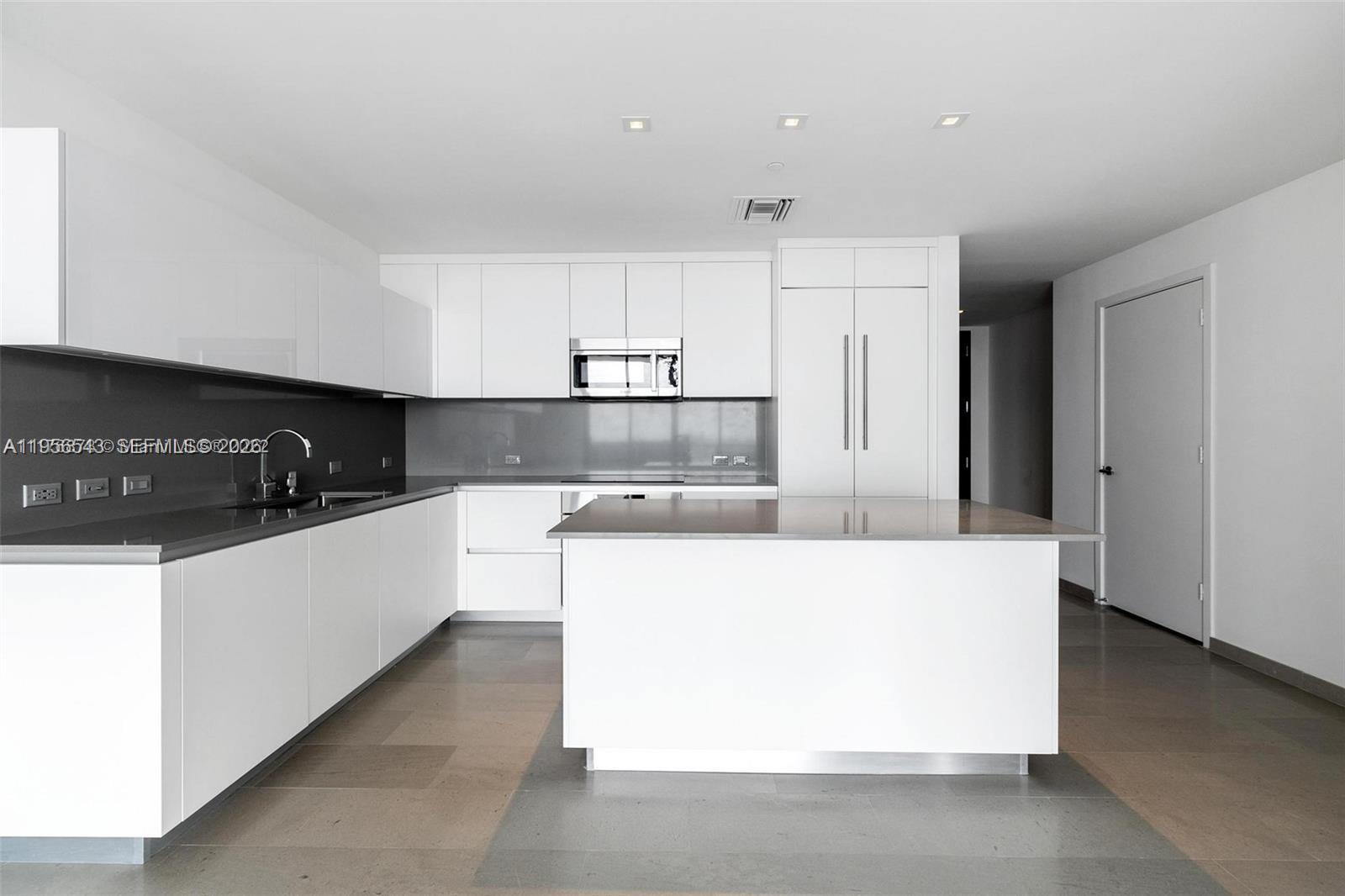 88 Southwest 7th Street, Unit 2104 Miami, FL 33130 - Photo 8 of 50 a large white kitchen with kitchen island a sink stainless steel appliances and cabinets