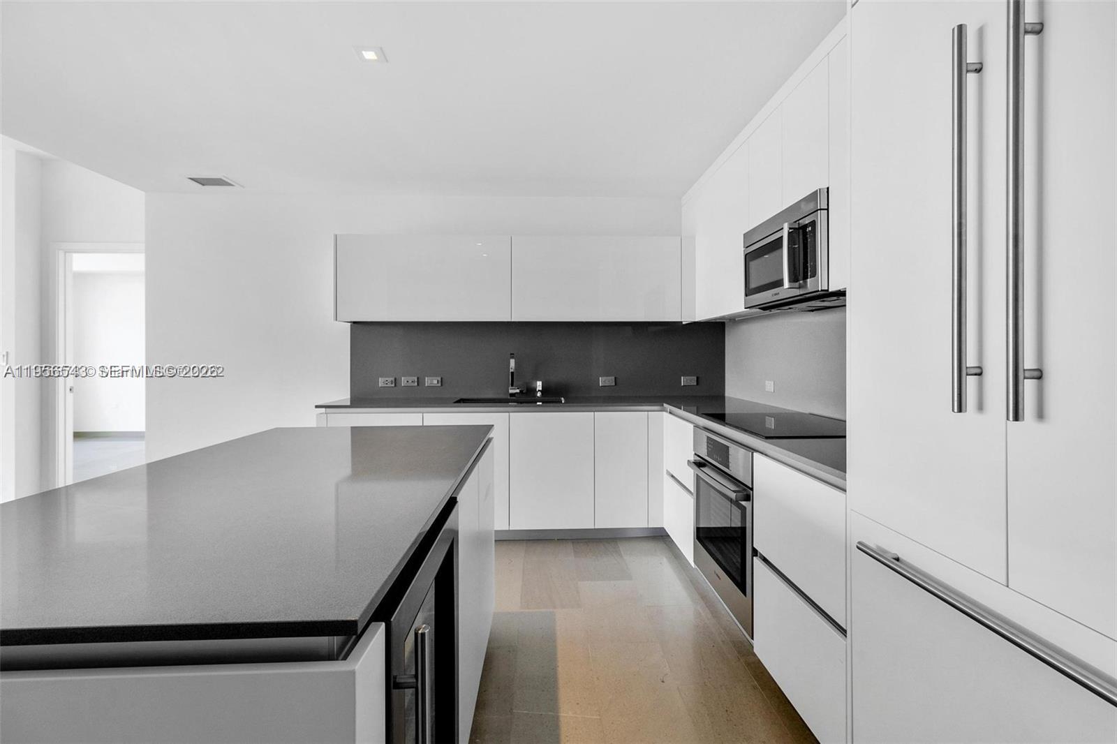 88 Southwest 7th Street, Unit 2104 Miami, FL 33130 - Photo 10 of 50 a kitchen with stainless steel appliances a sink a stove top oven a counter space and cabinets