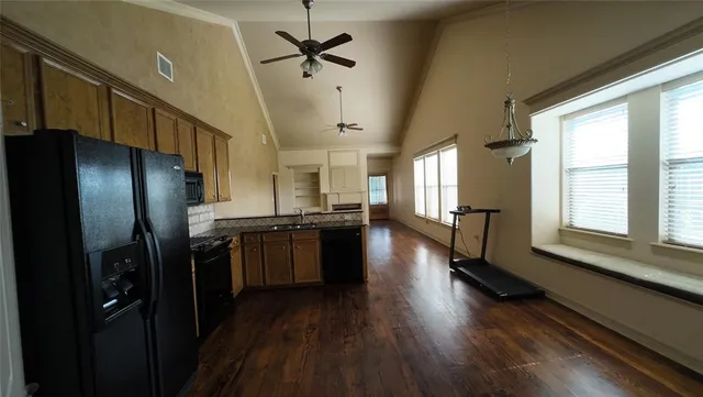 a kitchen with stainless steel appliances granite countertop a refrigerator a sink dishwasher a stove and a dining table with wooden floor