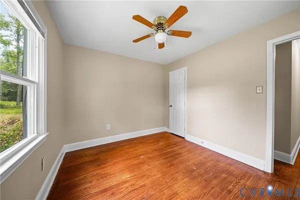 a view of an empty room with window and wooden floor