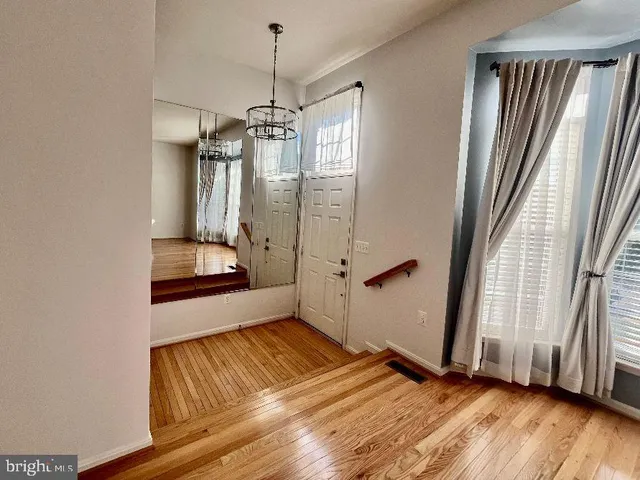 a view of empty room with wooden floor and window