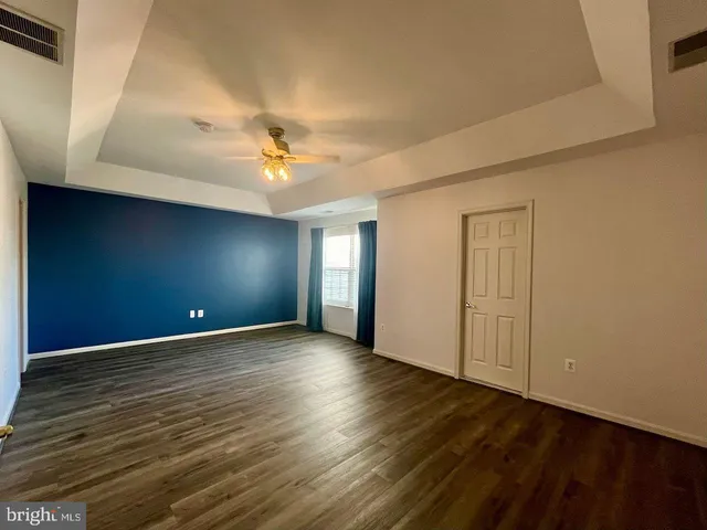 a view of an empty room with window and a ceiling fan