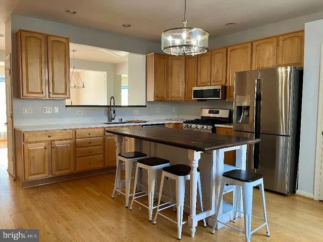 a kitchen with kitchen island granite countertop stainless steel appliances a stove a refrigerator and a dining table