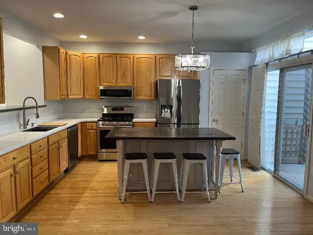 a kitchen with kitchen island granite countertop a sink a counter top space stainless steel appliances and cabinets