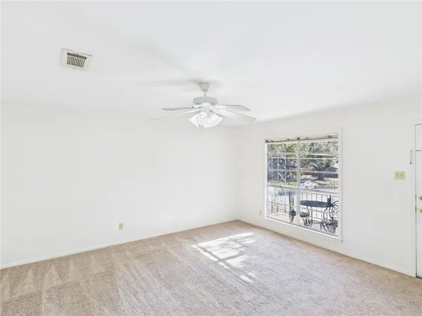 an empty room with windows and fan