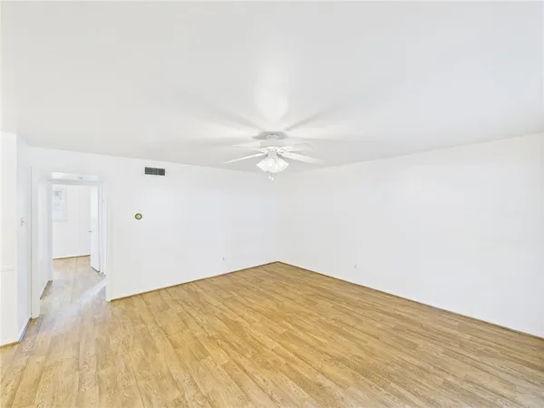 an empty room with wooden floor and fan