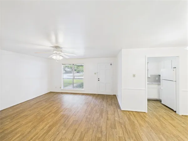 an empty room with wooden floor cabinet and windows