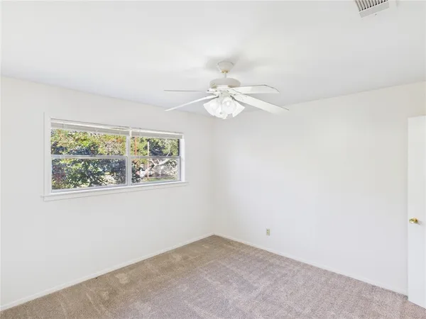 an empty room with a window and a fan
