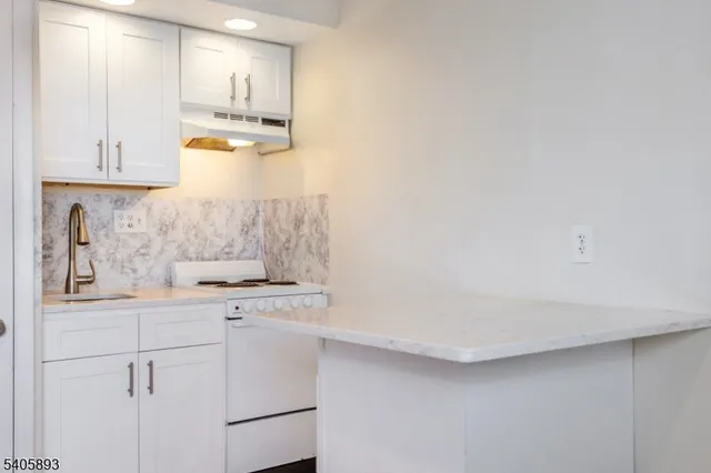 a kitchen with white cabinets and sink