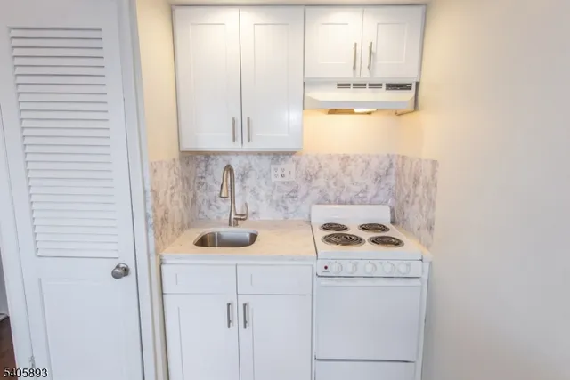 a kitchen with white cabinets and sink