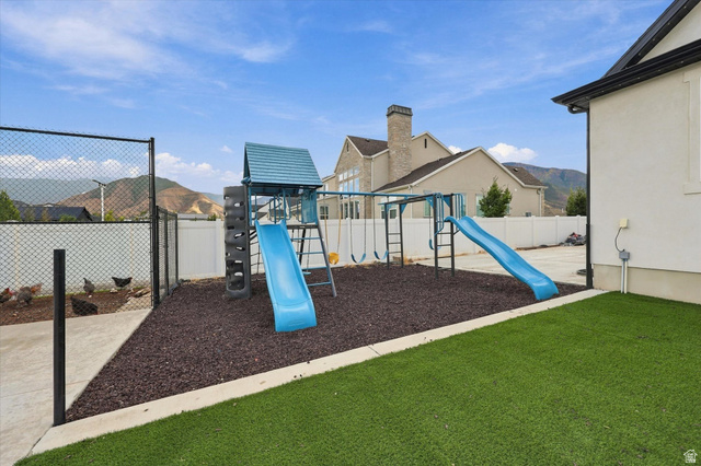 754 West 400 North Mapleton, UT 84664 - Photo 73 of 86 Artificial turf lawn, built-in play structure with slides and swings, chain link fencing, white privacy fencing, and concrete patio area.