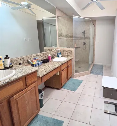 a spacious bathroom with a granite countertop sink a mirror and a shower