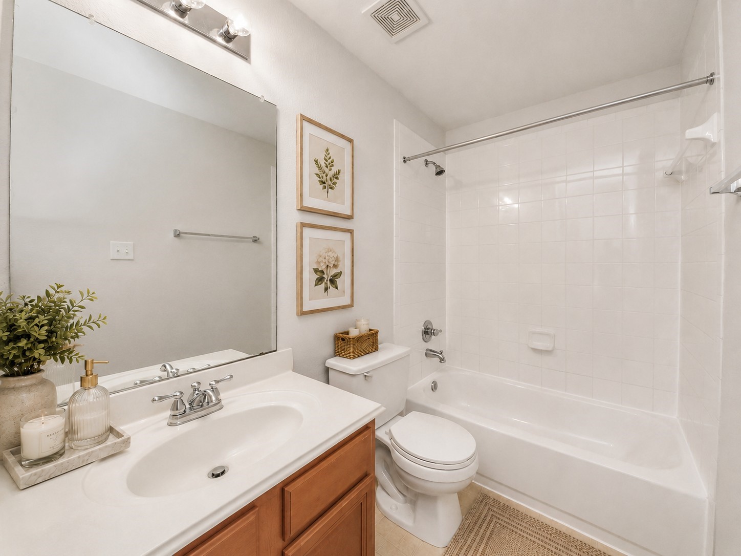 2930 Ribbon Creek Way Spring, TX 77389 - Photo 15 of 25 Bright and inviting bathroom features a sleek white vanity, a spacious mirror, and a pristine bathtub with tiled walls, complemented by tasteful decor.