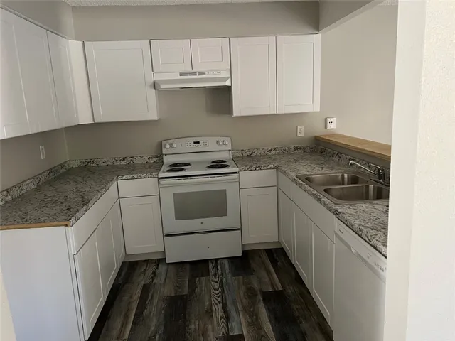 a kitchen with granite countertop white cabinets and white appliances