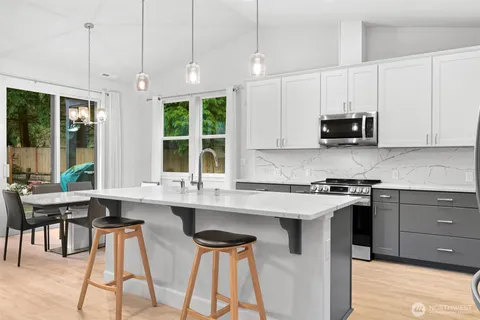 a kitchen with a sink dishwasher a refrigerator a stove top oven a wooden floor and cabinets