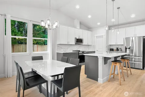 a kitchen with stainless steel appliances granite countertop a stove top oven a sink a dining table and chairs