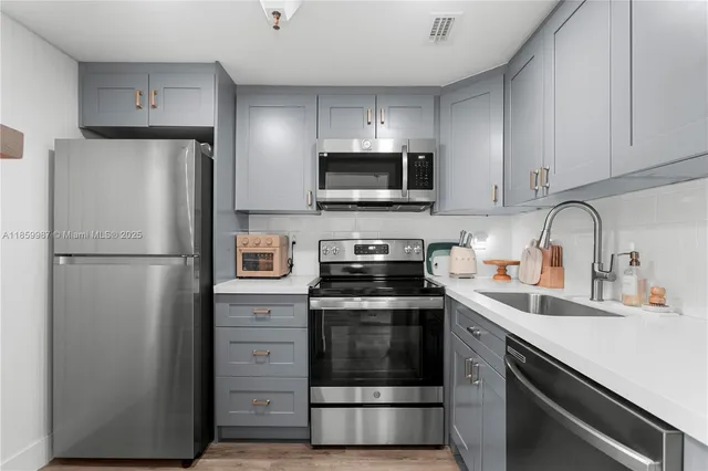 a kitchen with refrigerator a microwave a sink and cabinets
