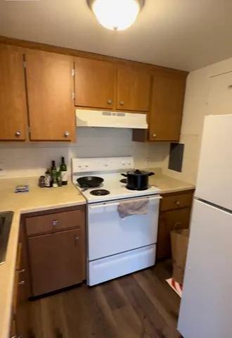 a kitchen with a sink a stove wooden cabinetry and refrigerator