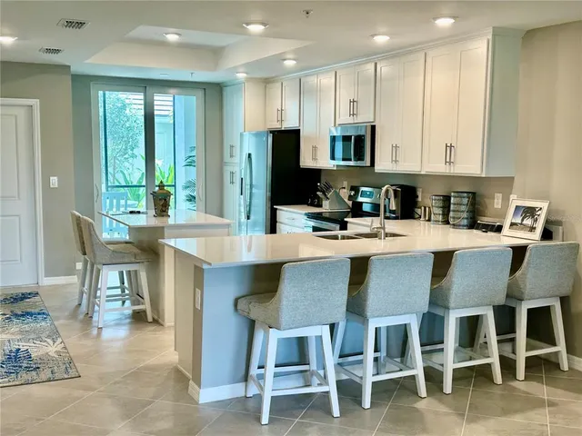 a kitchen with stainless steel appliances a sink a stove a refrigerator cabinets and a kitchen island