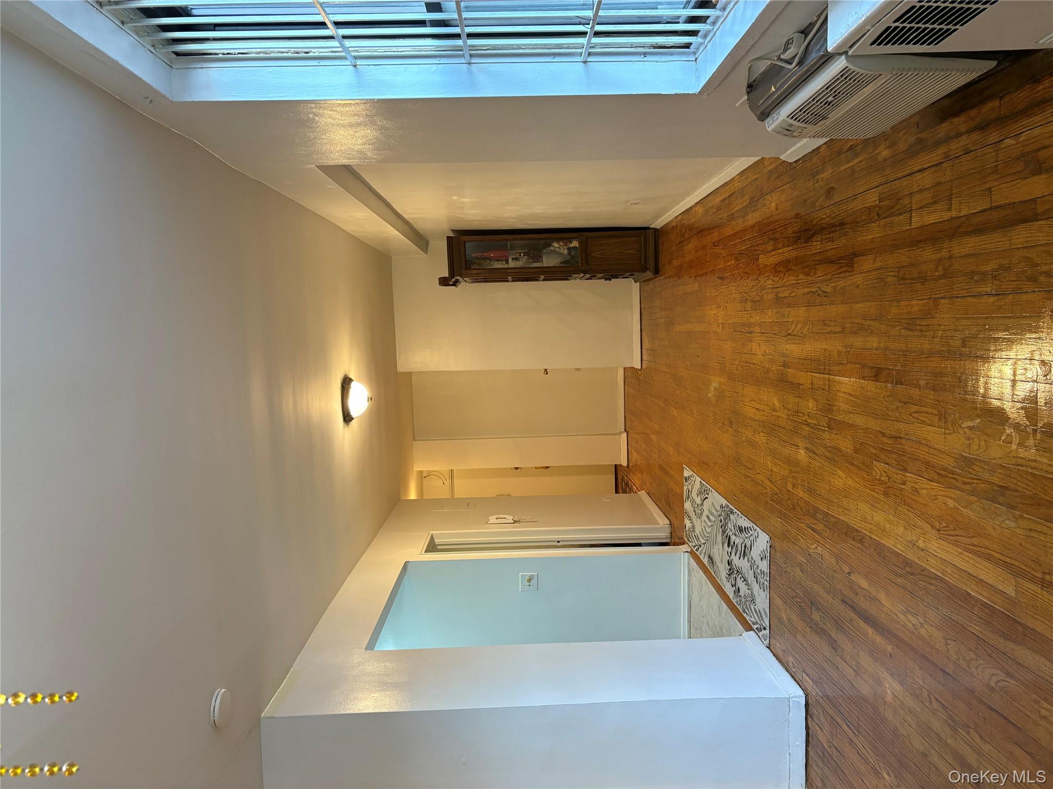 41-31 51st Street, Unit 6M Queens, NY 11377 - Photo 2 of 23 Empty room with baseboards, wood finished floors, and a wall mounted AC