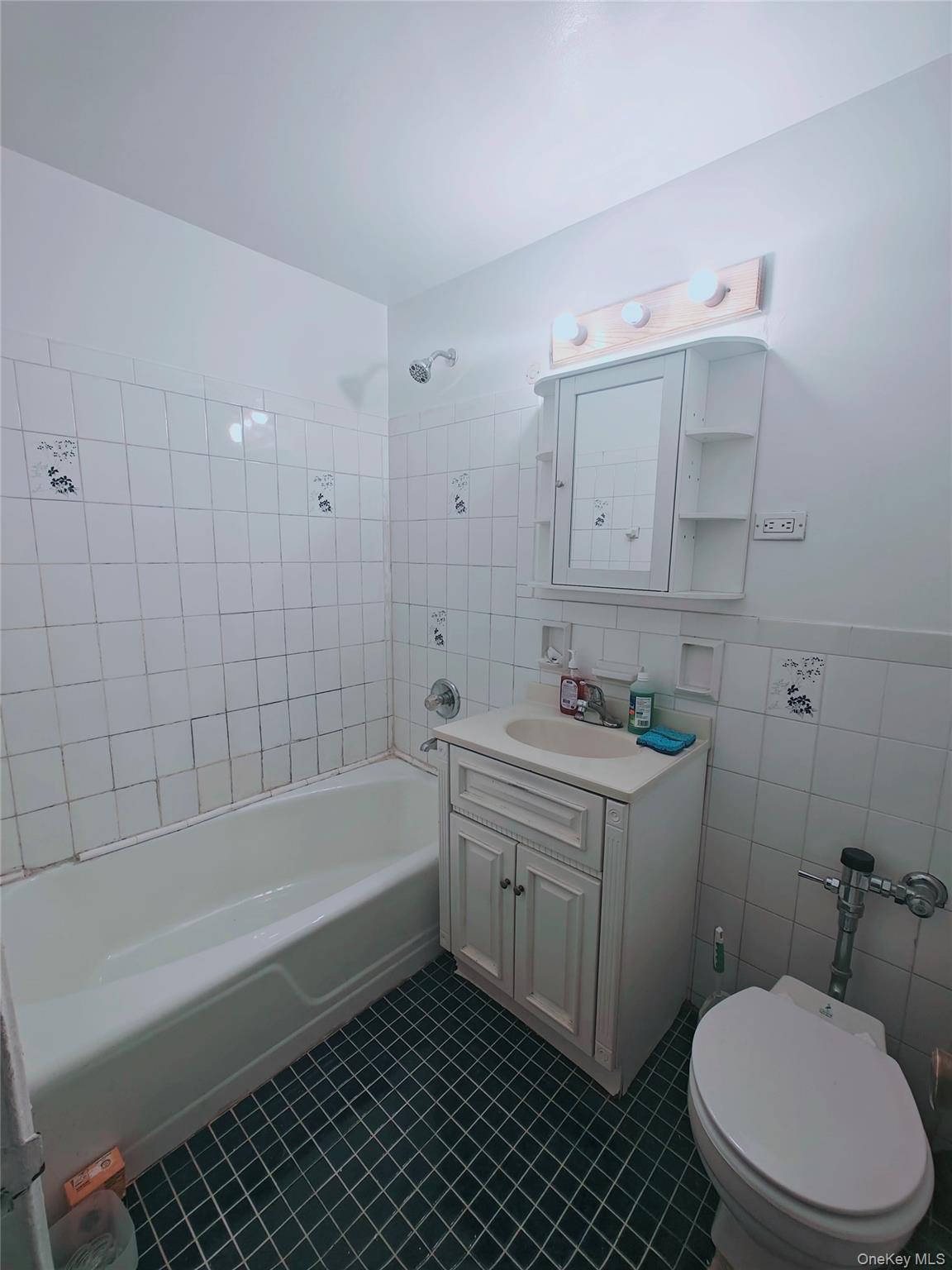 41-31 51st Street, Unit 6M Queens, NY 11377 - Photo 21 of 23 Full bathroom featuring vanity, tile patterned floors, tiled shower / bath, toilet, and tile walls