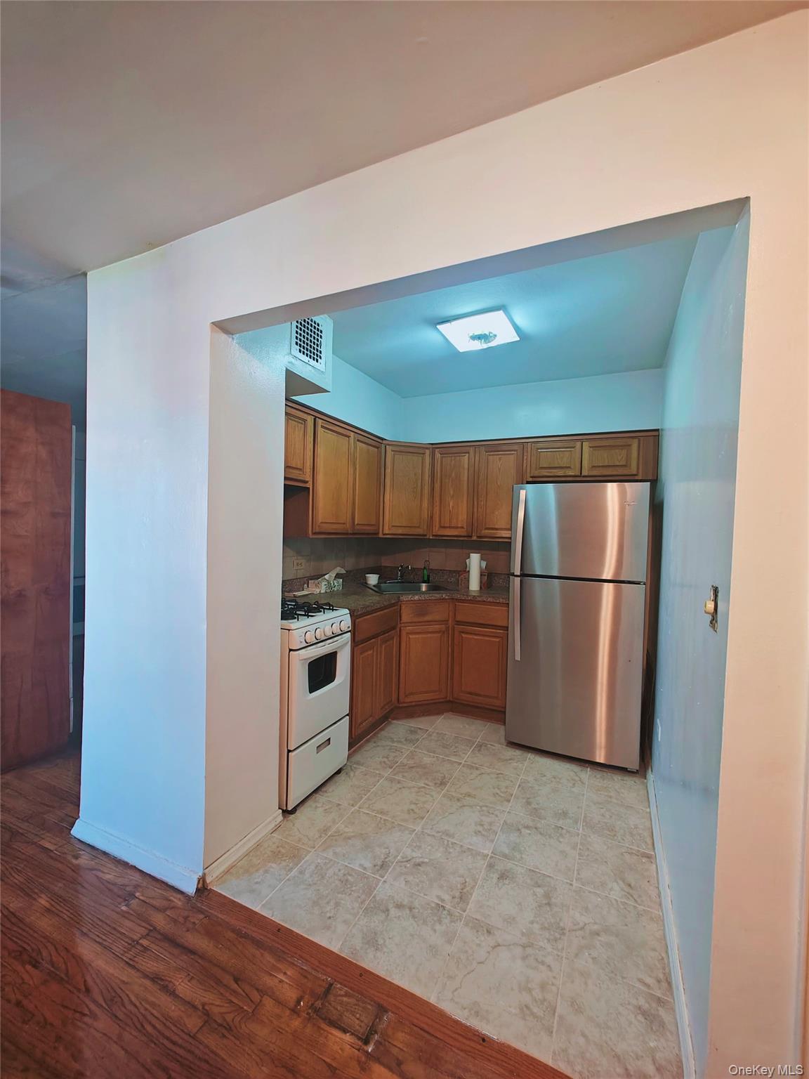 41-31 51st Street, Unit 6M Queens, NY 11377 - Photo 6 of 23 Kitchen featuring white gas range oven, light hardwood / wood-style flooring, stainless steel refrigerator, and sink