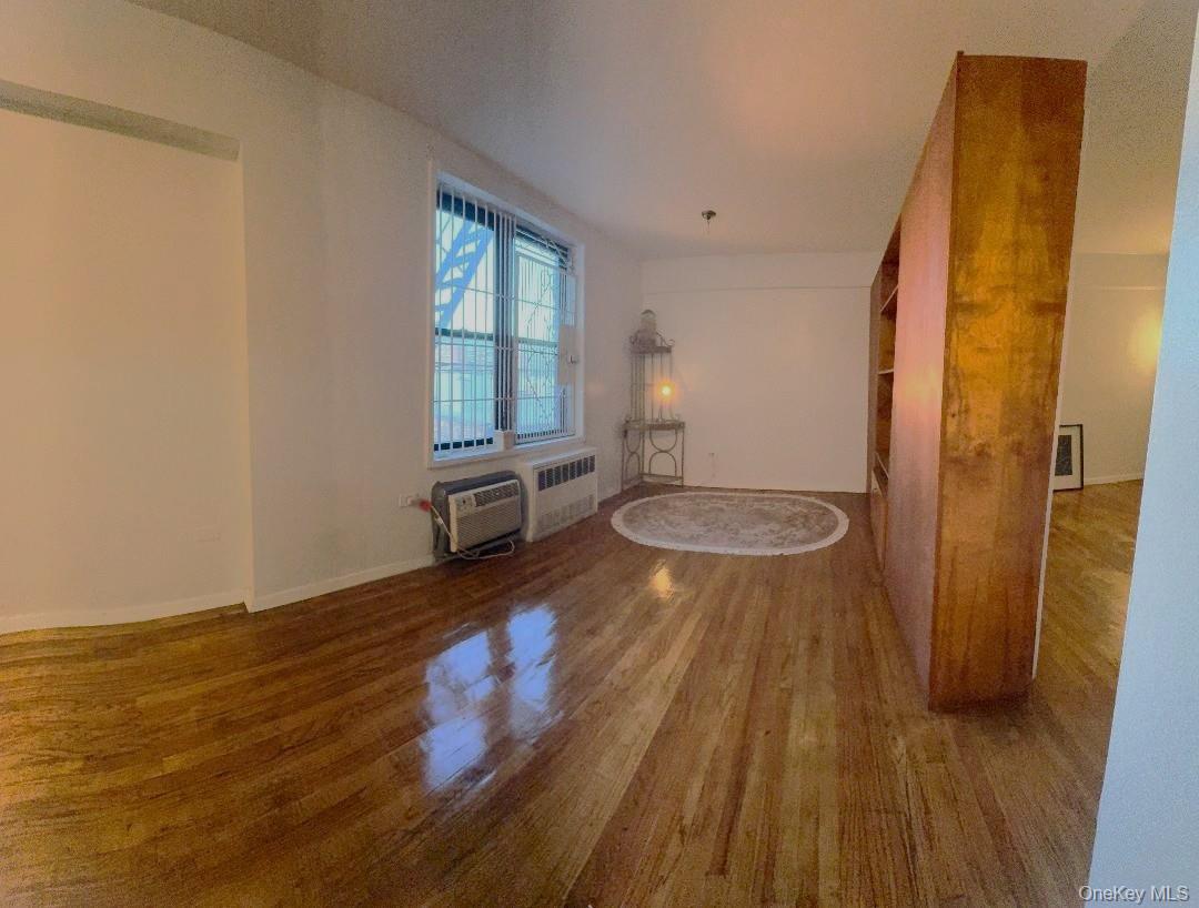 41-31 51st Street, Unit 6M Queens, NY 11377 - Photo 10 of 23 Spare room featuring wood finished floors and radiator