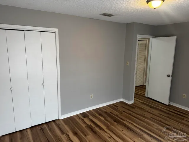 a view of an empty room with wooden floor and closet