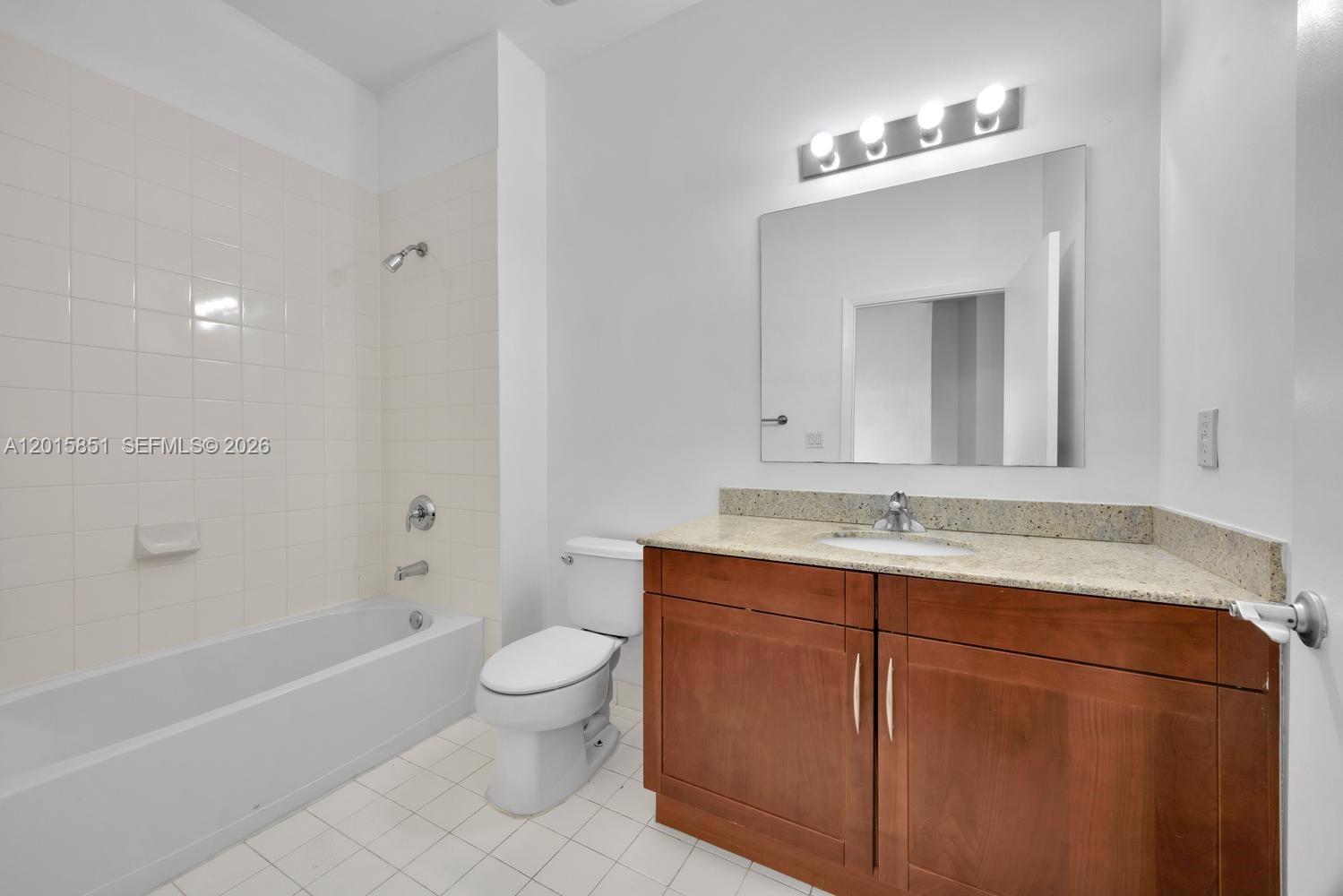 7275 Southwest 90th Street, Unit C719 Miami, FL 33156 - Photo 19 of 25 a bathroom with a granite countertop sink a toilet mirror and bathtub