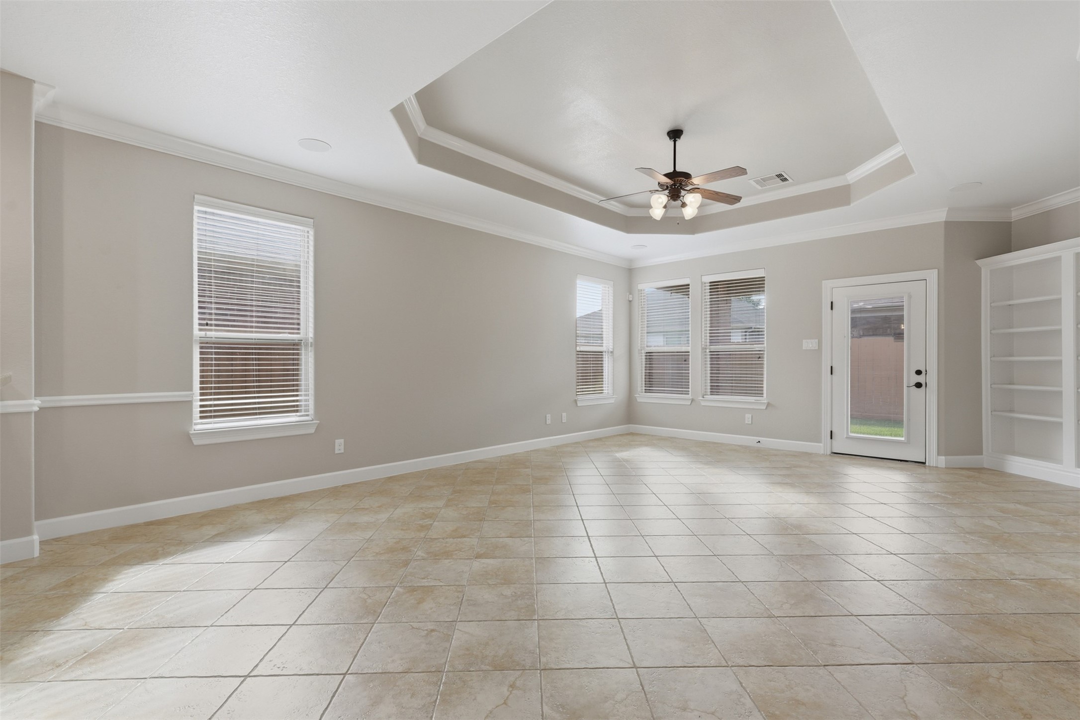 721 Rufina Street League City, TX 77573 - Photo 10 of 33 The spacious family room impresses with an elegant tray ceiling accented by crown molding, gleaming tile floors, and walls of windows that fill the space with natural light. A glass back door frames peaceful backyard views while providing effortless access to the covered patio.