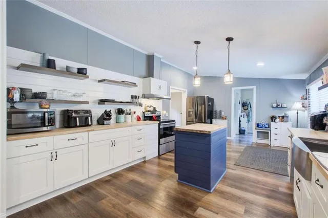 a large kitchen with stainless steel appliances granite countertop a lot of counter space and wooden floors