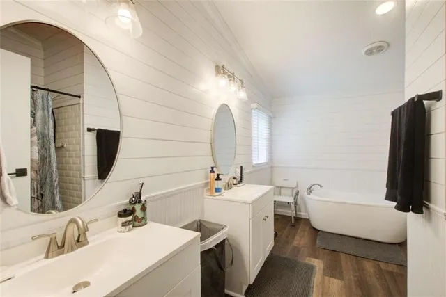 a bathroom with a double vanity sink a mirror and bathtub