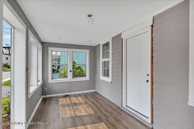 a view of an empty room with wooden floor and a window