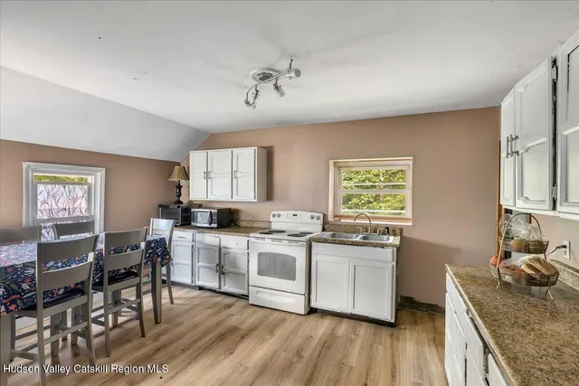 a kitchen with stainless steel appliances granite countertop a stove top oven a sink dishwasher and white cabinets with wooden floor