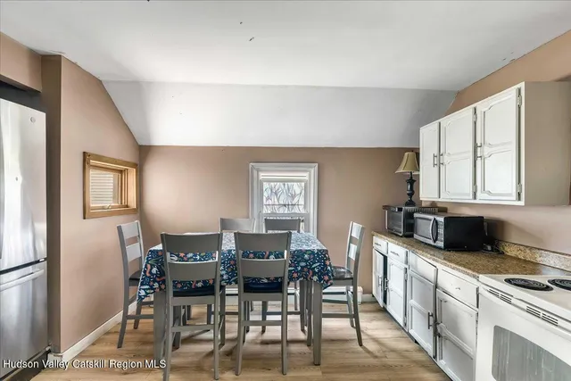 a kitchen with stainless steel appliances granite countertop a stove top oven a sink a dining table and chairs with wooden floor