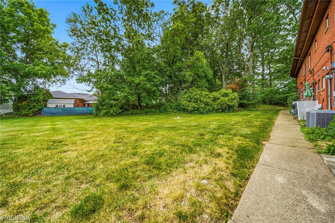1694 Ridgewick Drive Wickliffe, OH 44092 - Photo 28 of 30 Expansive green space featuring a concrete pathway, mature trees, and a brick exterior building