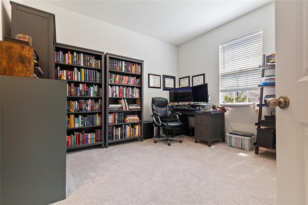 12401 Shining Willow Street Riverview, FL 33579 - Photo 7 of 26 a view of a workspace with furniture and a bookshelf
