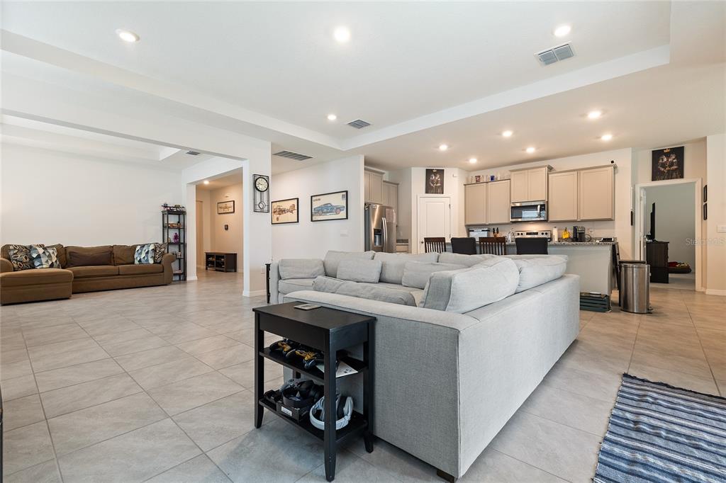 12401 Shining Willow Street Riverview, FL 33579 - Photo 8 of 26 a large white kitchen with stainless steel appliances kitchen island granite countertop a large counter top a couches and cabinets