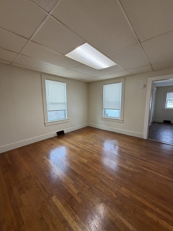 90 Bacon Street, Unit 1 Waltham, MA 02451 - Photo 4 of 9 an empty room with wooden floor and windows